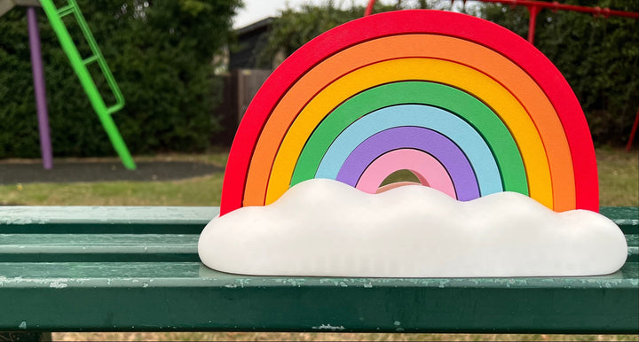 Colorful rainbow decoration on a green bench with a playground in the background