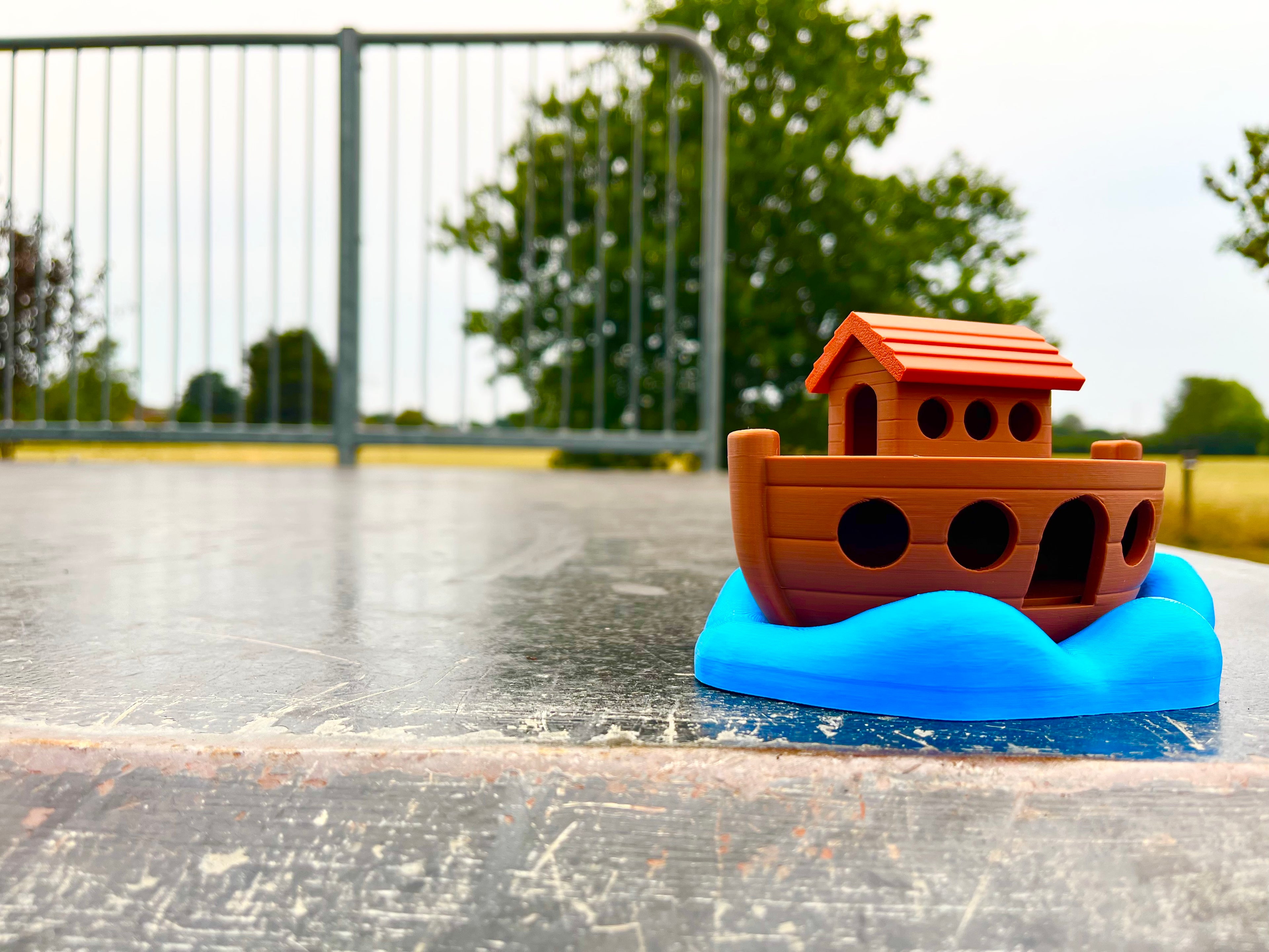 Toy Noah's Ark on a flat metal ramp with trees in the background