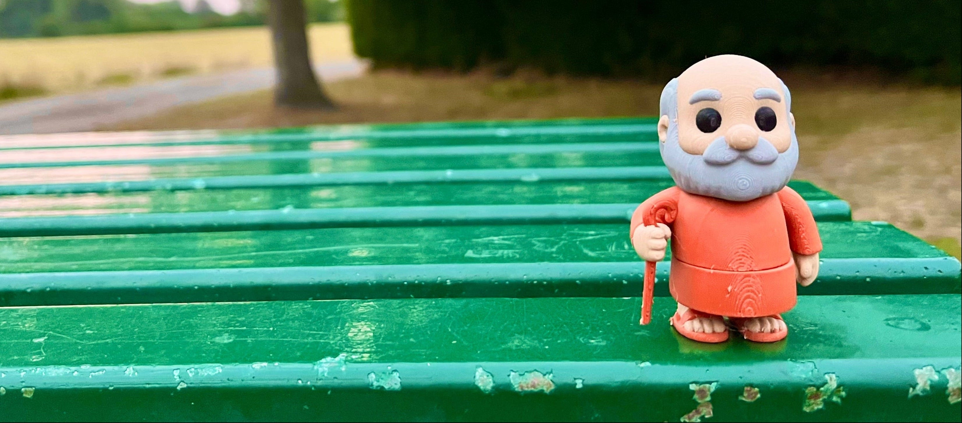 Toy figure of a monk on a green bench with a natural background