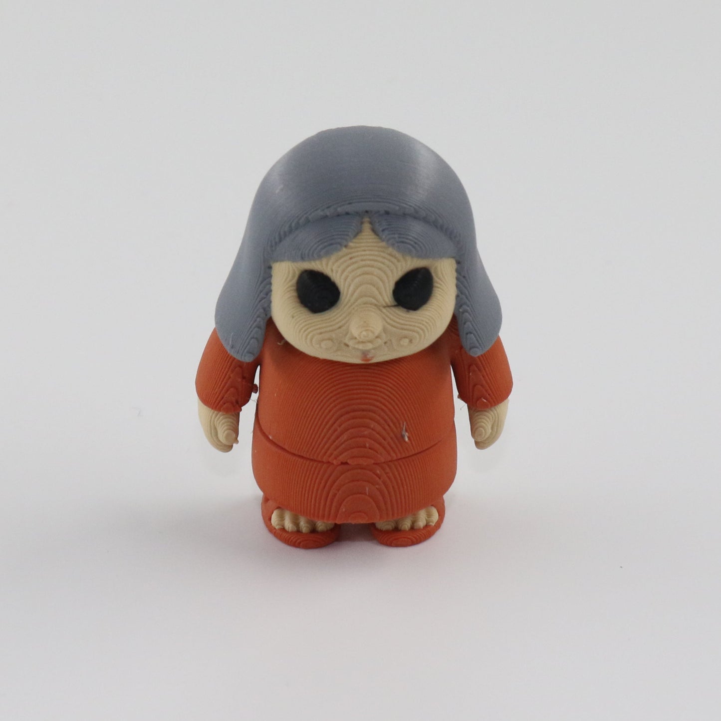 Small figurine with gray hair and brown outfit on a white background