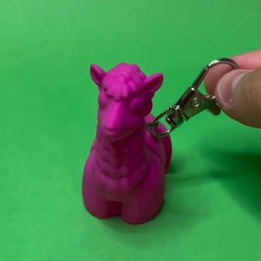 Pink alpaca-shaped keychain on a green back