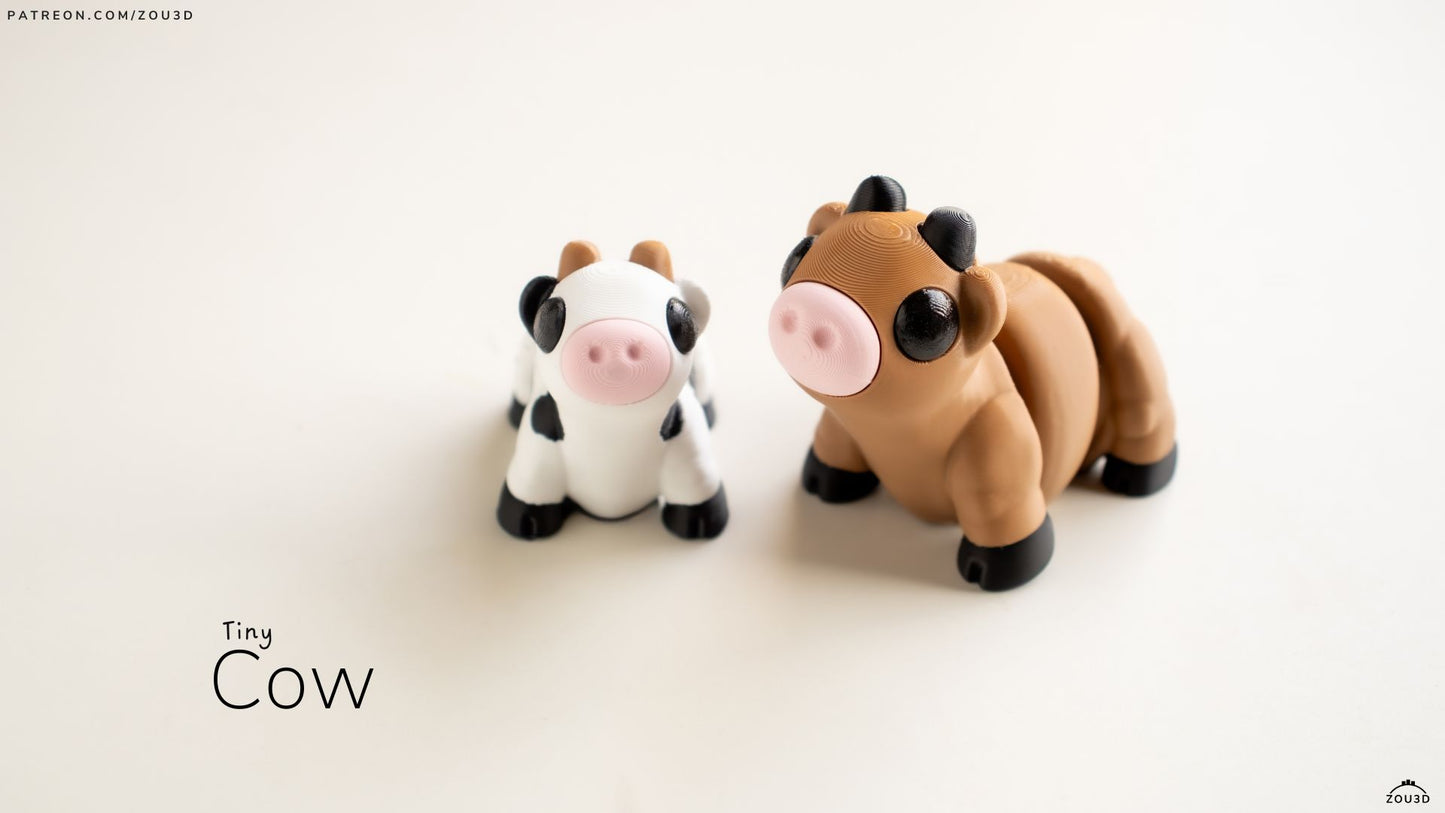 Two small cow figurines, one black and white and one brown, on a light background.