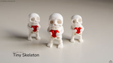 Three small skeleton figures holding red hearts on a neutral background