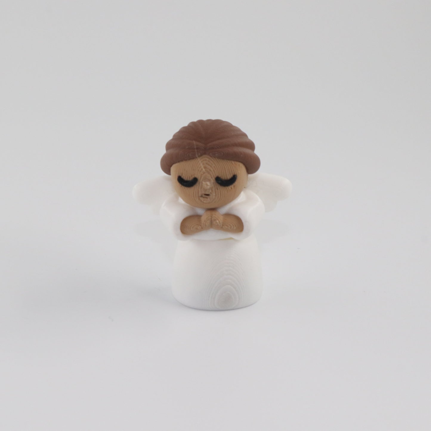 Small figurine of a person with brown hair and a white outfit on a light gray background