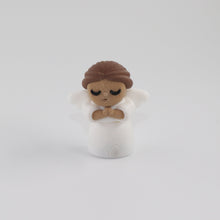 Small figurine of a person with brown hair and a white outfit on a light gray background
