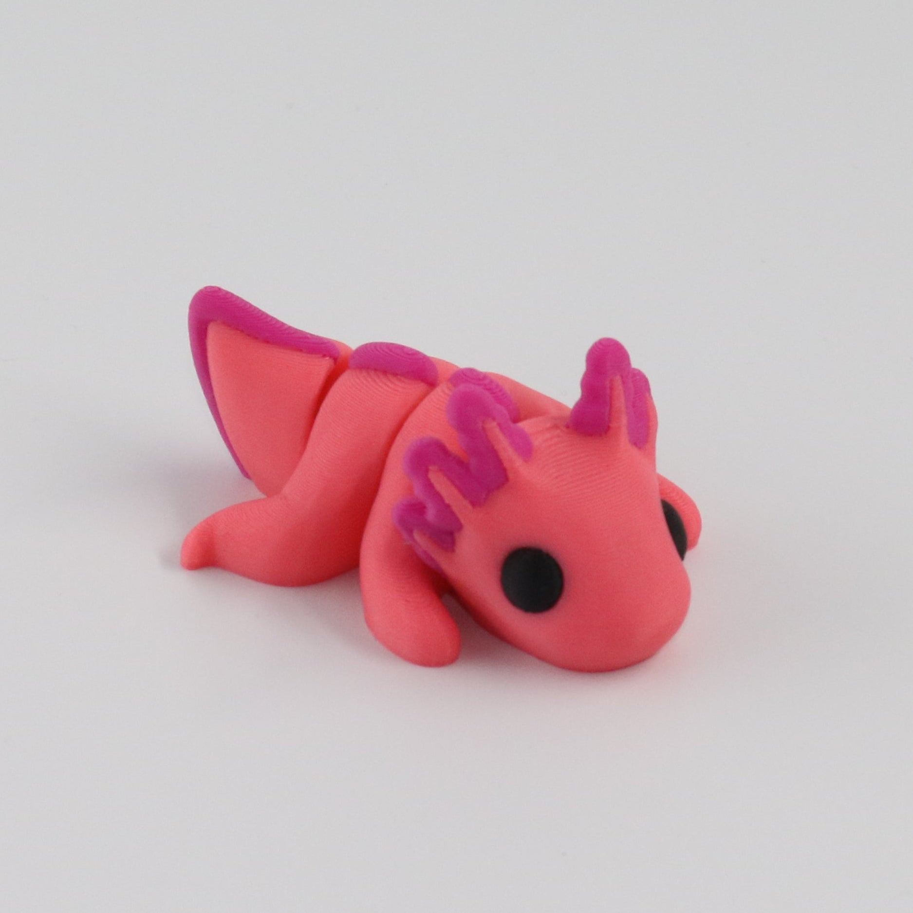 Small pink axolotl figurine on a light white background