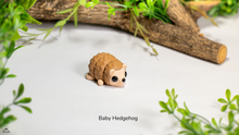 Articulated toy hedgehog on a light surface with greenery