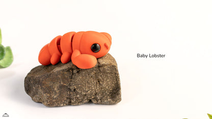 Model of a baby lobster on a rock with a white background