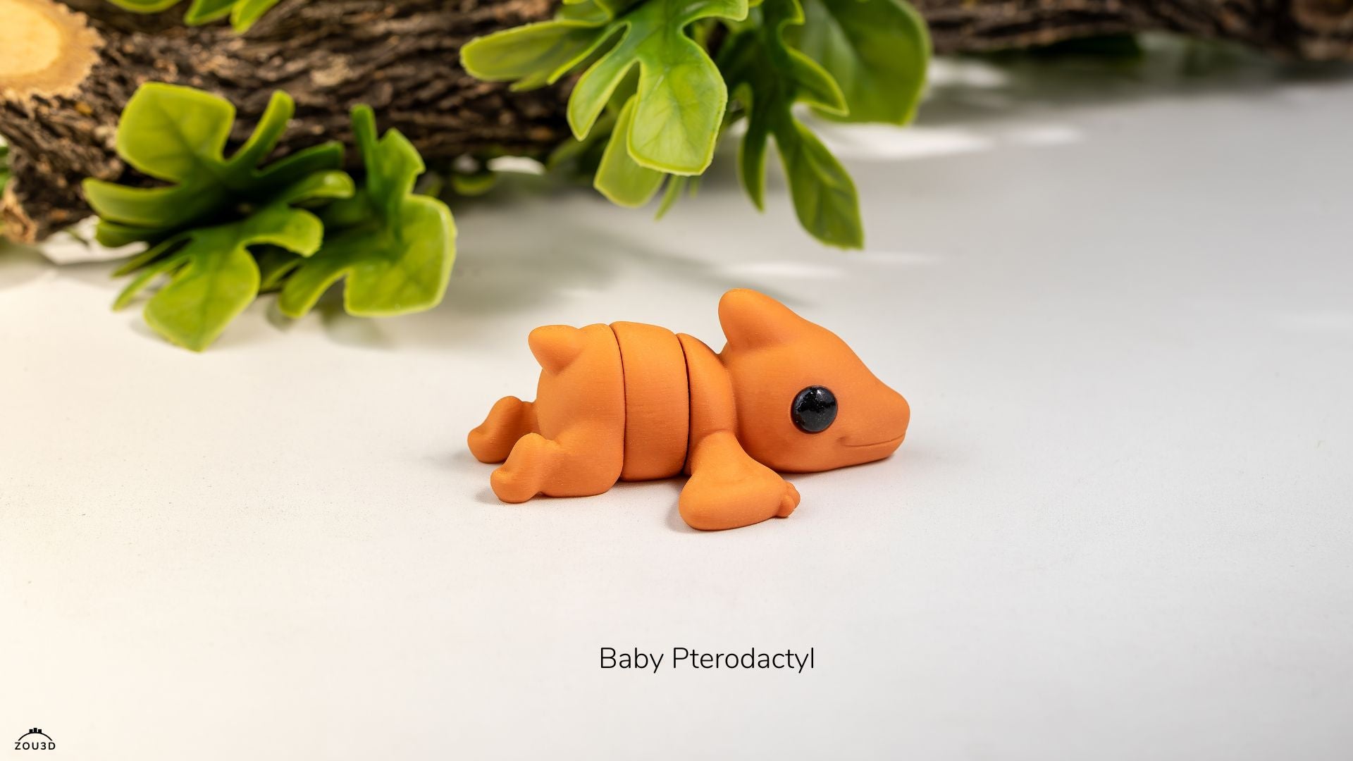 Baby pterodactyl figurine on a white surface with green leaves in the background