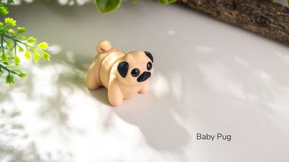 Small figurine of a baby pug on a light surface with greenery in the background