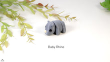 Model of a baby rhino on a white background with green leaves
