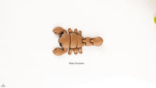Articualted toy resembling a baby scorpion on a white background
