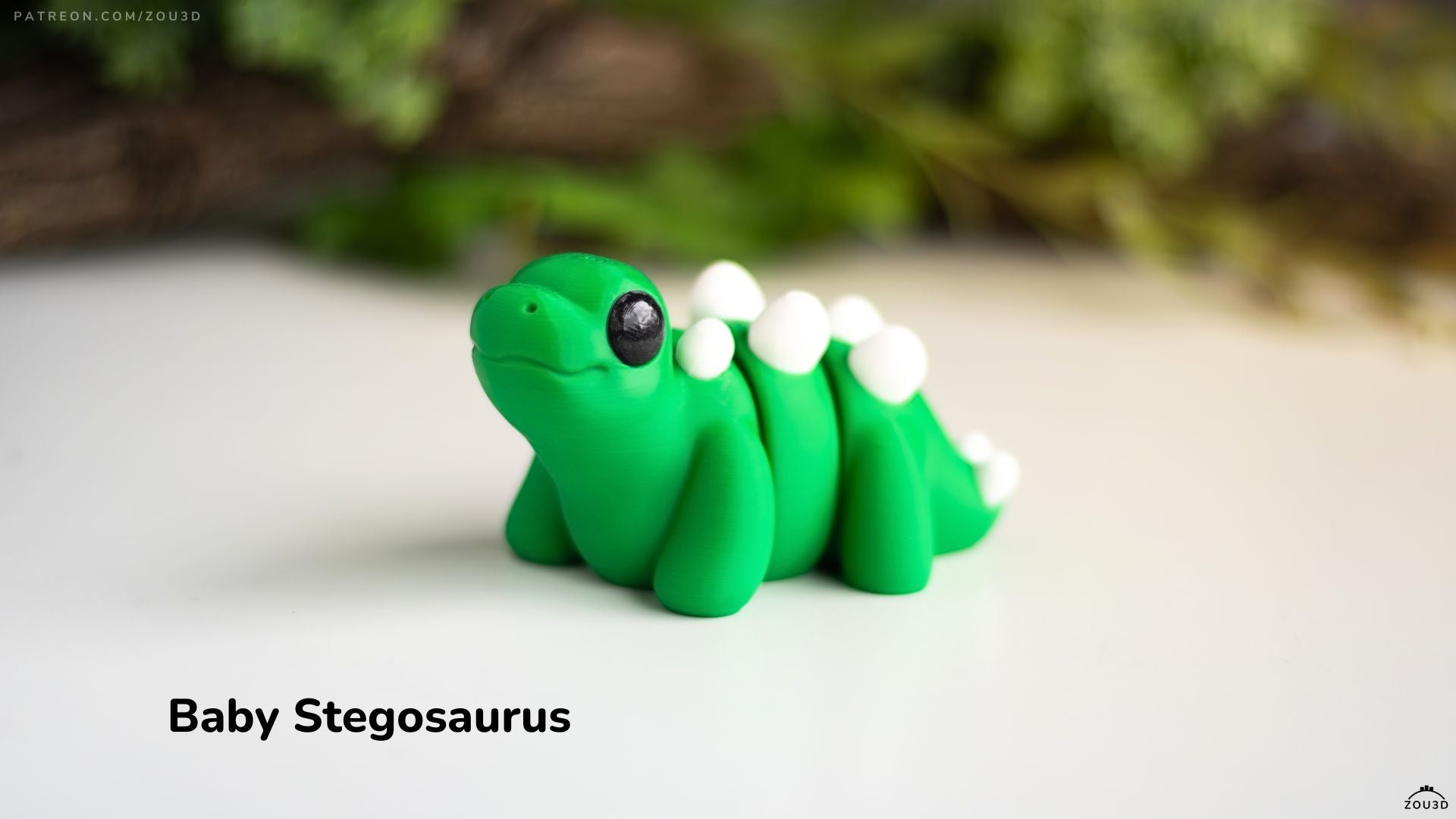 Model of a baby stegosaurus on a white surface with a blurred green background