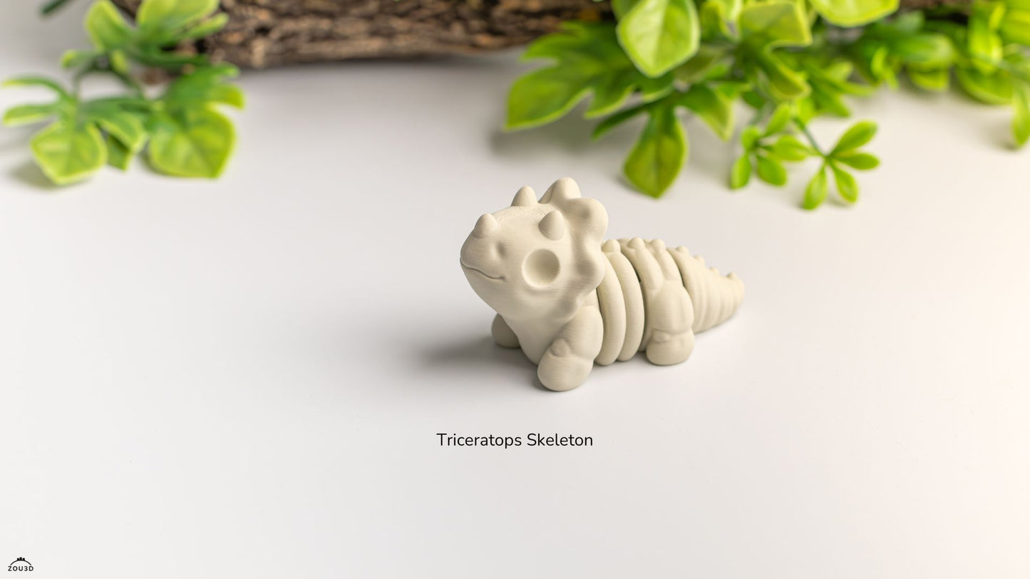 White triceratops skeleton model on a light surface with green leaves in the background