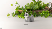 Gray wolf figurine with 'Baby Wolf' text on a white background with greenery.