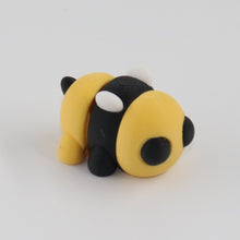 Small black and yellow bee-shaped object on a white background