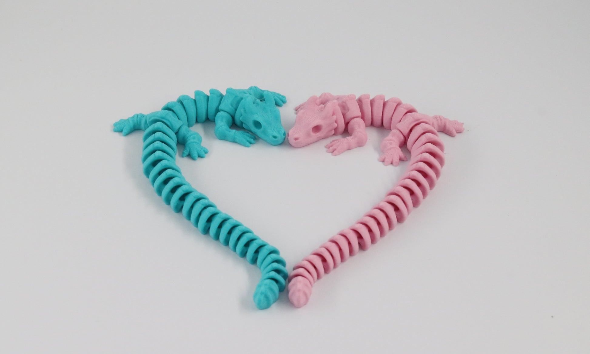 Two flexible, articulated dragon toys in pink and blue on a light white background