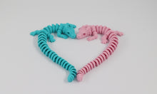 Two flexible, articulated dragon toys in pink and blue on a light white background