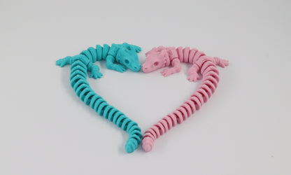 Two flexible, articulated dragon toys in pink and blue on a light white background