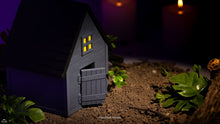 Small model of a haunted house with glowing windows on a dark background