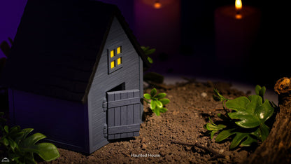Small model of a haunted house with glowing windows on a dark background