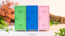 Three colorful mini lockers (green, blue, pink) on a white surface with a blurred natural background.