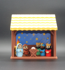 Nativity scene figurine set in a manger with a dark gray background