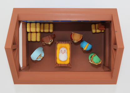 Miniature nativity scene with figurines in a wooden crib on a white background