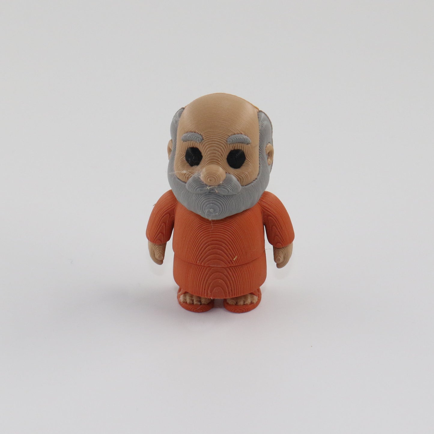 Small figurine of an elderly man in a brown outfit on a white background