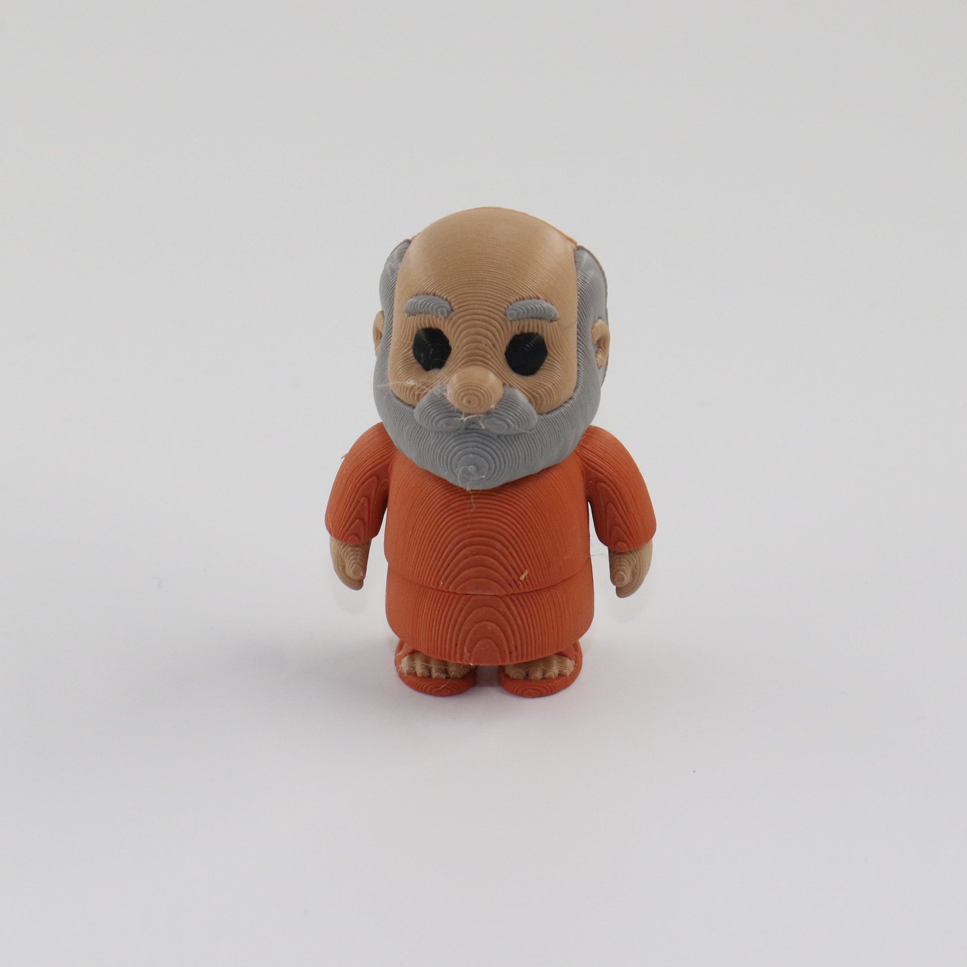 Small figurine of an elderly man in a brown outfit on a white background
