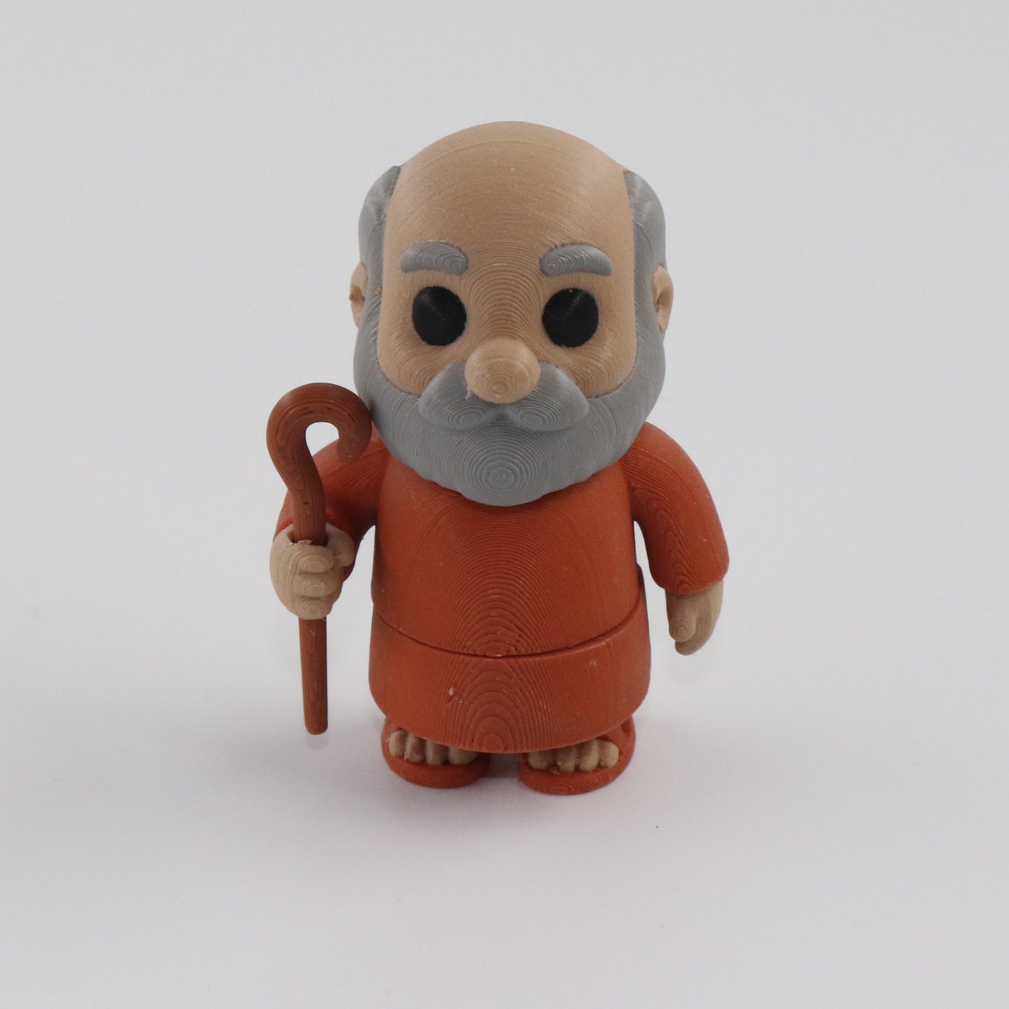 Toy figure of an elderly man with a walking stick on a white background