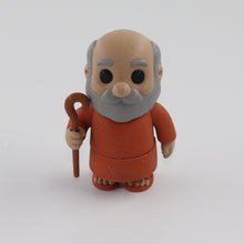 Toy figure of an elderly man with a walking stick on a white background