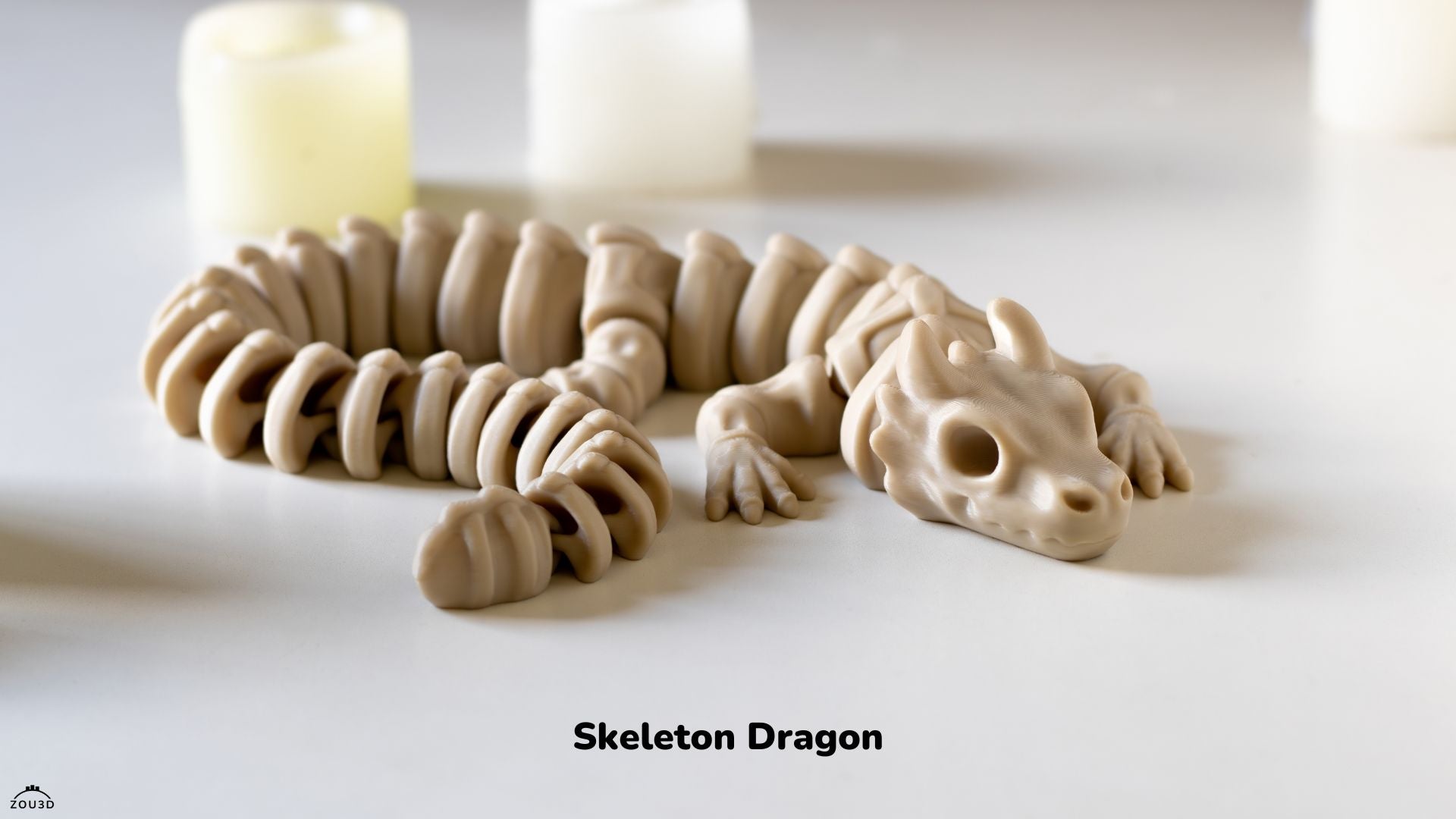 Model of a skeleton dragon on a white surface with candles in the background