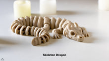 Model of a skeleton dragon on a white surface with candles in the background