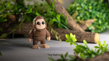 Small brown toy figure of a creature with a forest background