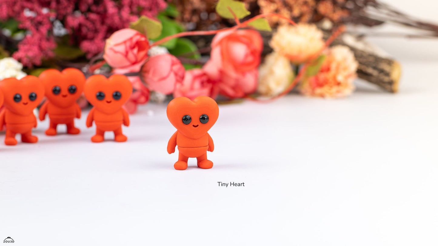 Small red figurines with black eyes and mouth on a white surface with flowers in the background.