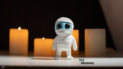 Toy figure of a mummy with glowing eyes on a dark background with candles