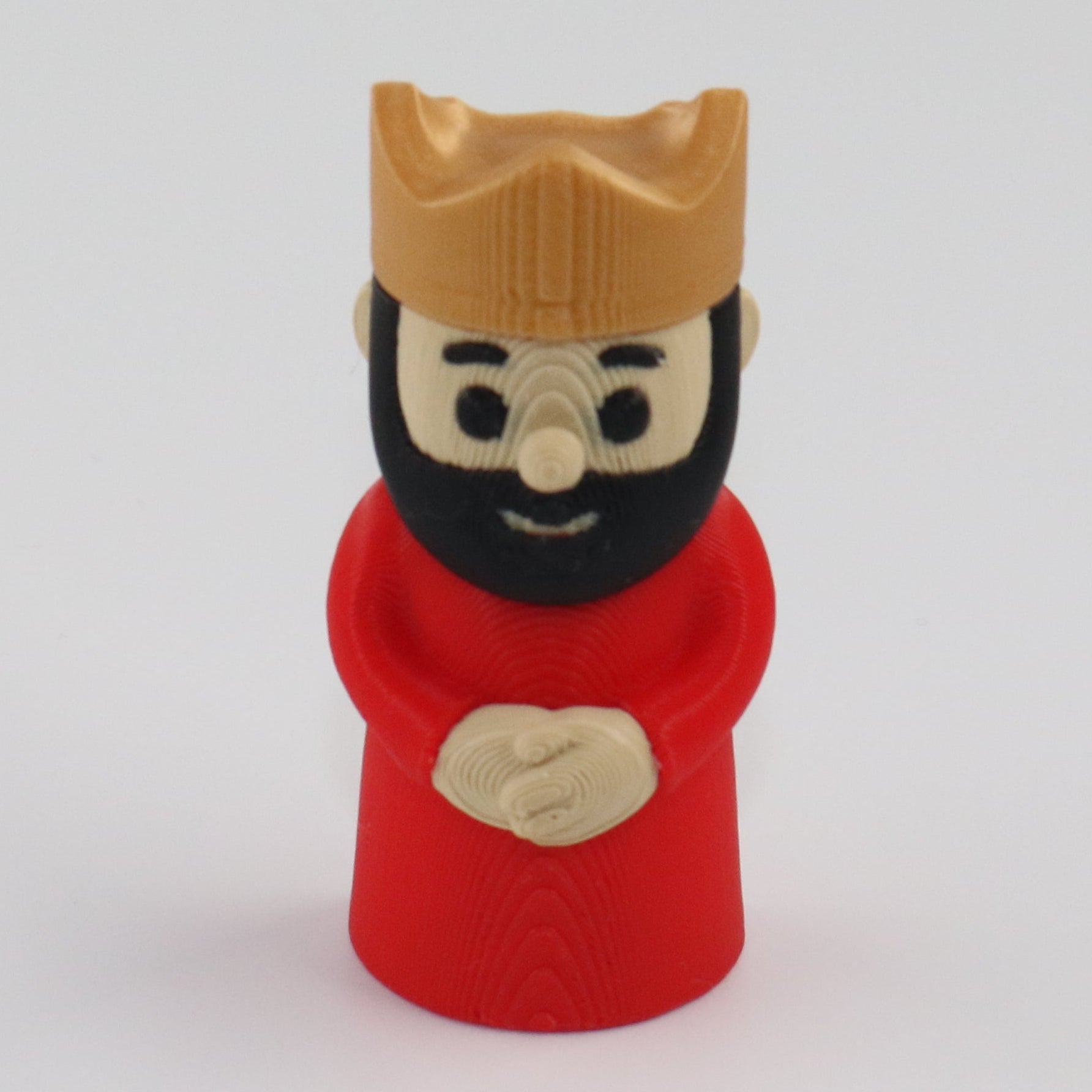 Small figurine of a bearded king wearing a red robe and gold crown on a white background