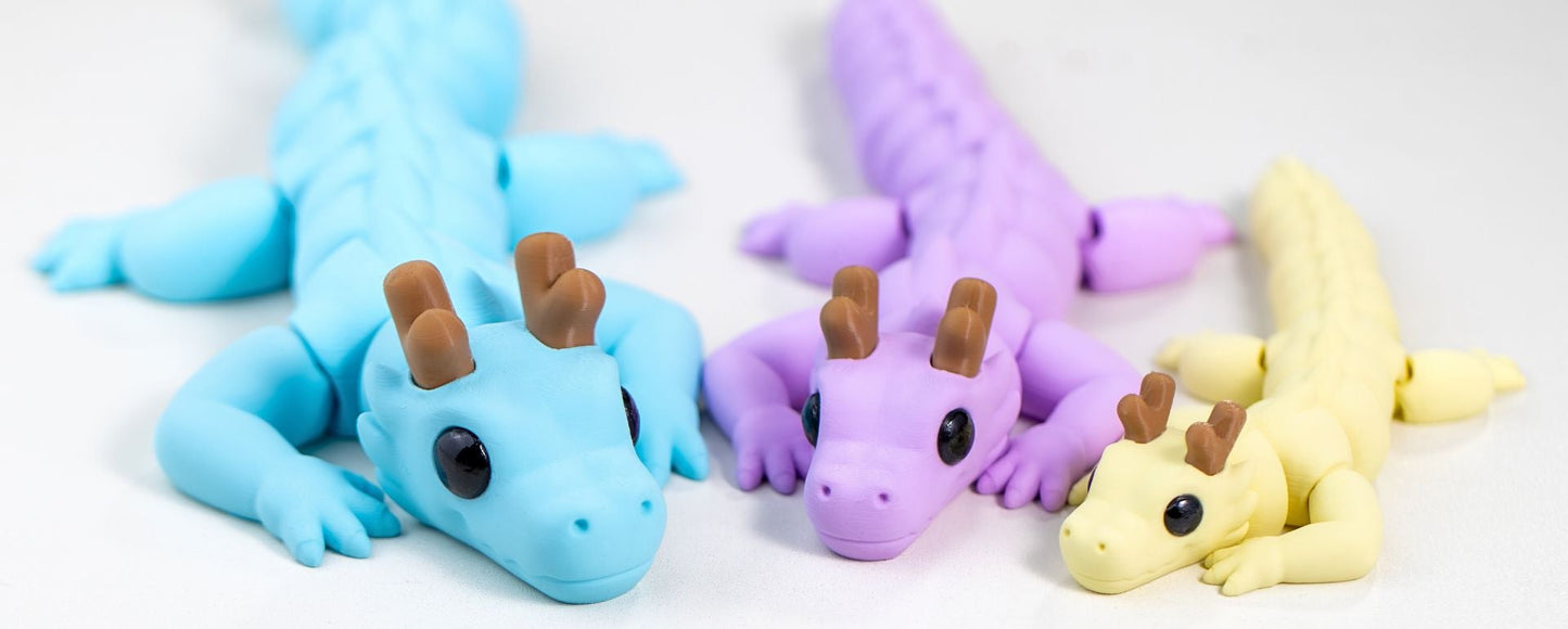 Three colorful mini dragon toys in blue, purple, and yellow on a white background.